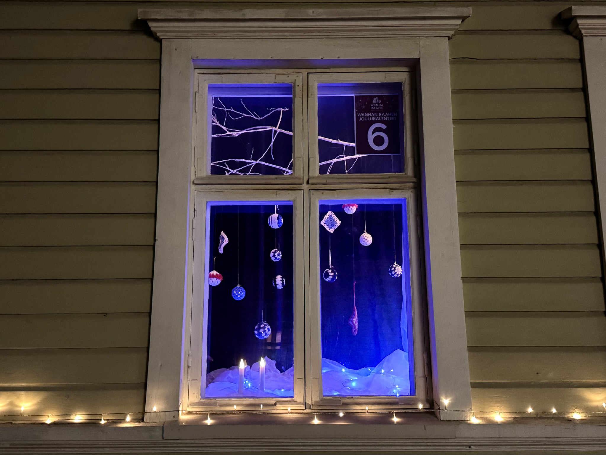 Old Town Raahe Advent Calendar window, where Christmas decorations are hanging from a branch of tree.