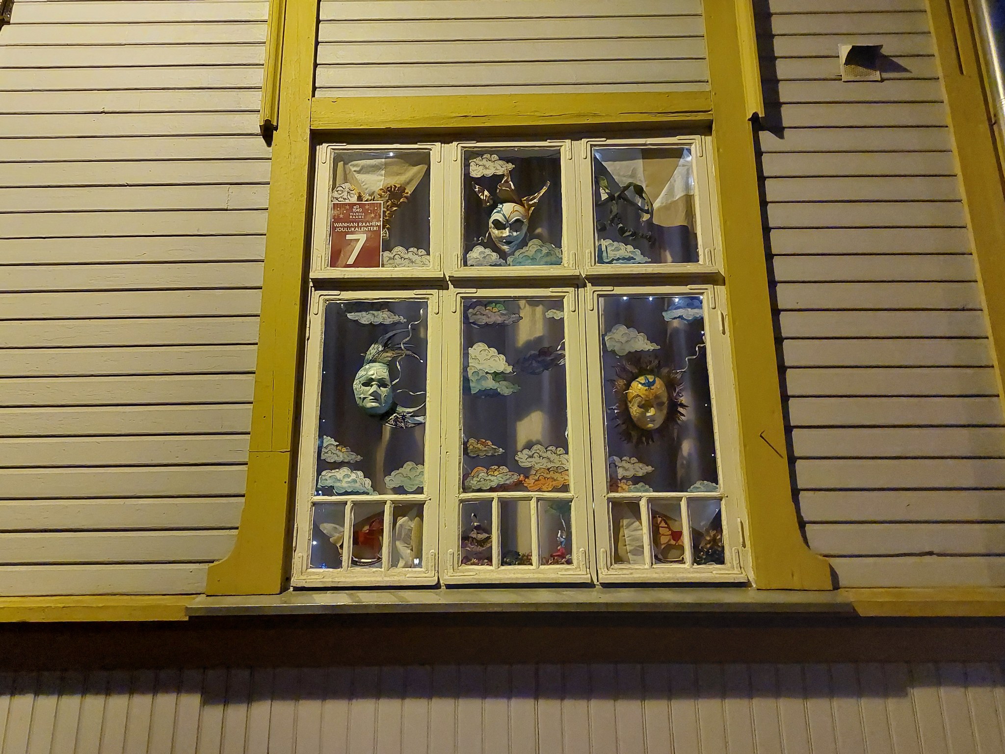 Old Town Raahe Advent Calendar window, where is masquerade masks and clouds.