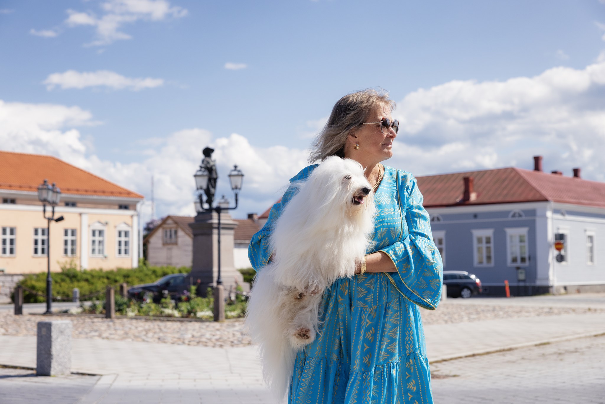 A woman holding a dog at Pekkatori Square in Old Town Raahe.