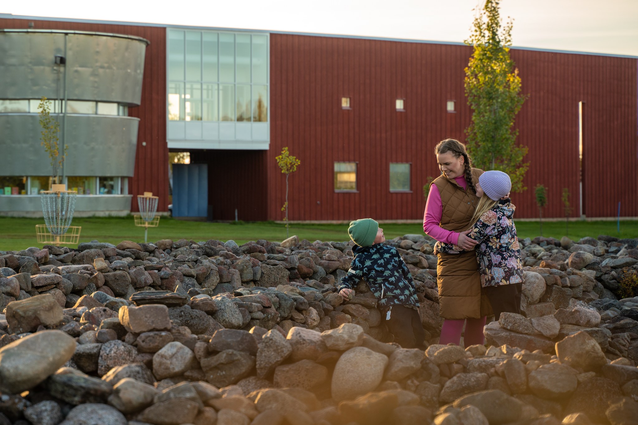 Äiti ja kaksi lasta syysmaisemissa Vihannin kirjaston edustalla.