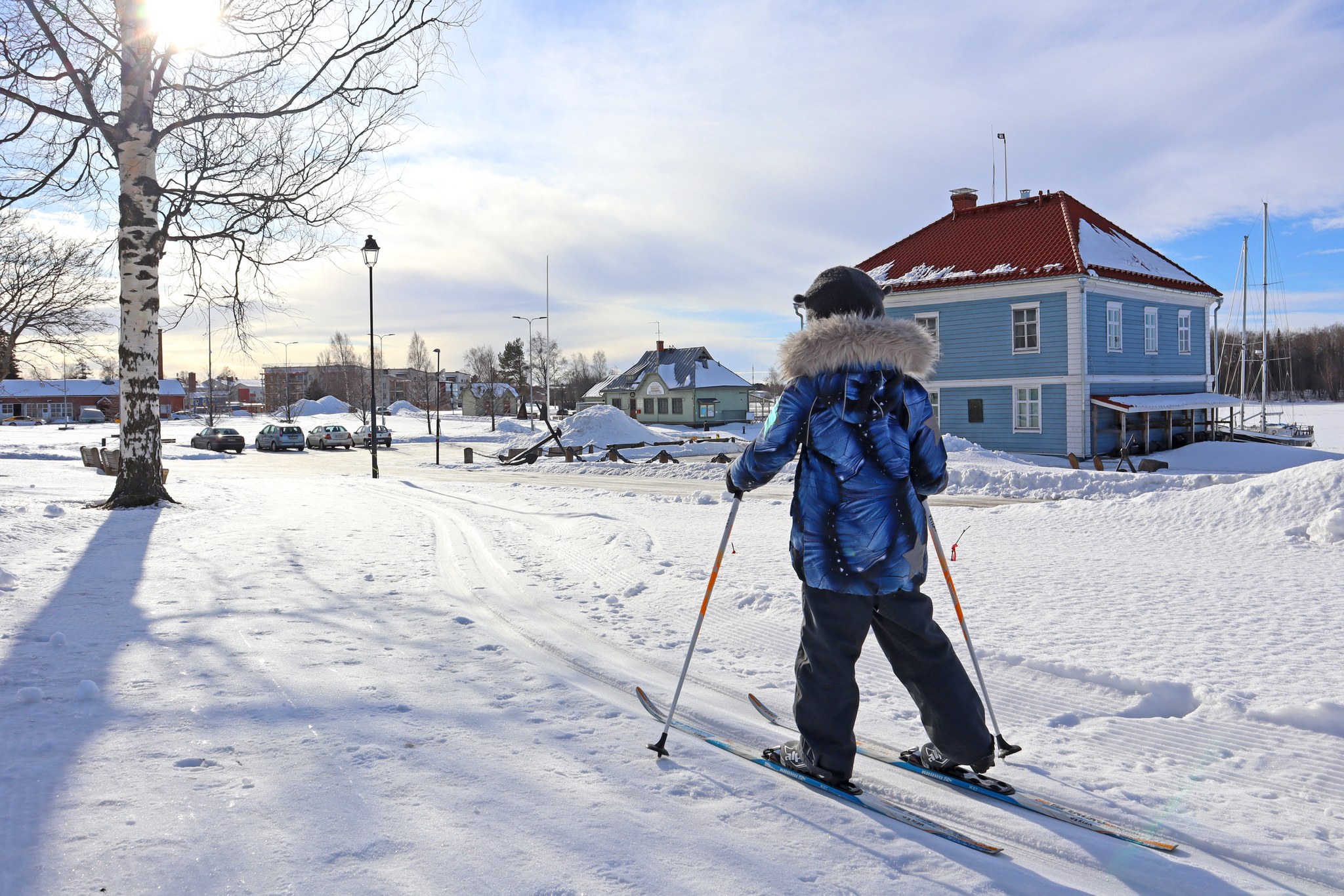 Lapsi hiihtämässä Raahen museonrannassa talvella, taustalla näkyy Pakkahuoneen museo