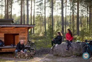 Pyöräilijät istuvat laavulla metsässä