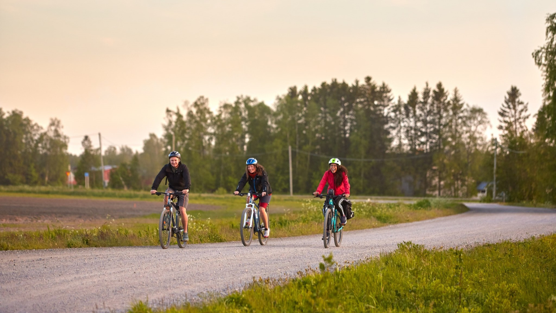 Three happy cyclists cycling on a gravel road