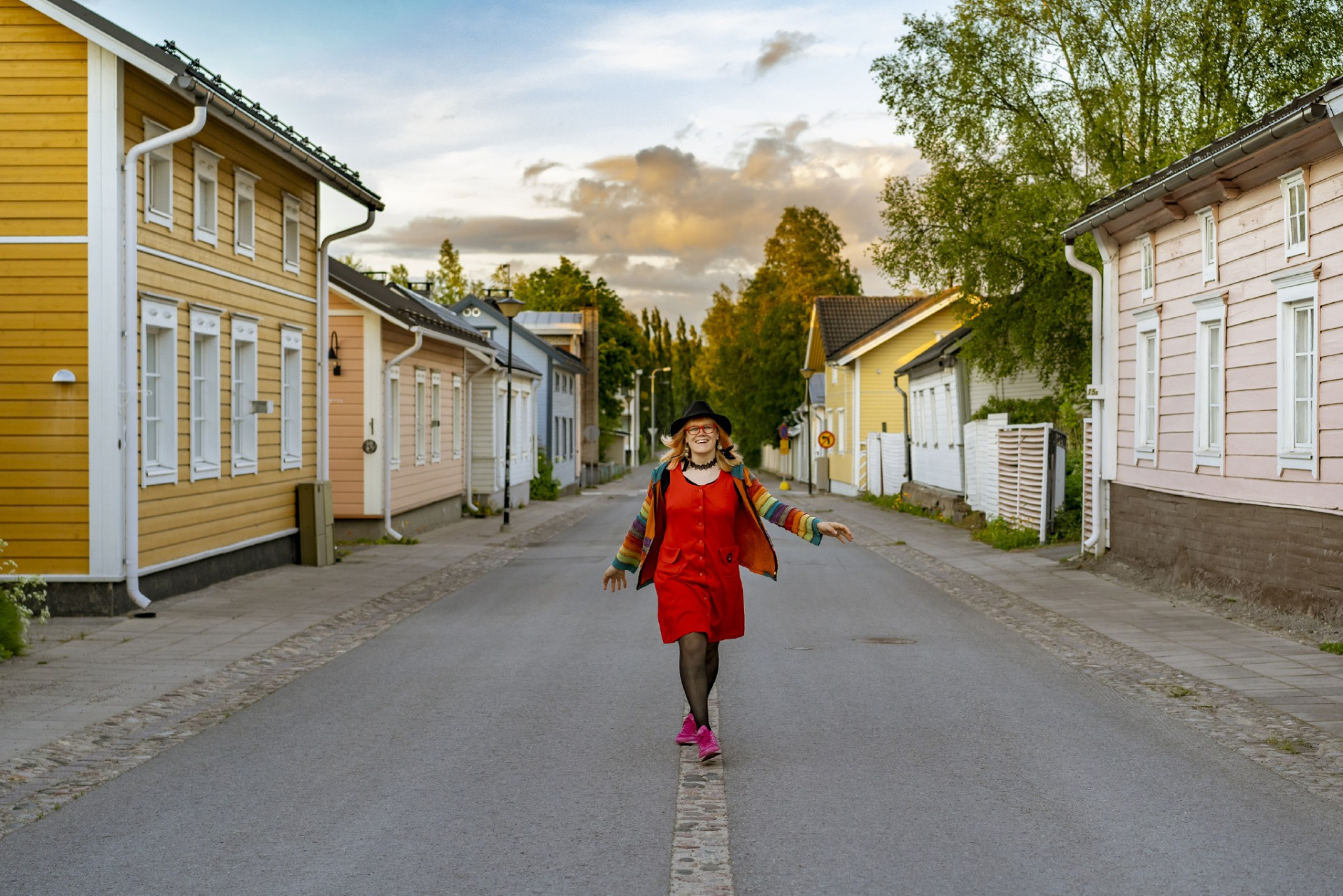 A person wearing a rainbow jacket while walking the streets of Old Town Raahe